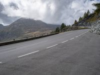 a person on a bike riding along the highway under a cloudy sky with mountains behind them