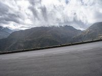 there is a person riding a bike on the road by the mountains in the rain