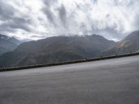 there is a person riding a bike on the road by the mountains in the rain