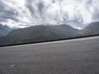 there is a person riding a bike on the road by the mountains in the rain