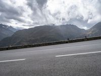 there is a person riding a bike on the road by the mountains in the rain