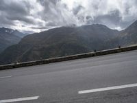 there is a person riding a bike on the road by the mountains in the rain