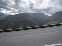 there is a person riding a bike on the road by the mountains in the rain