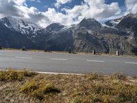 a motorcycle is parked on the side of the road with snow capped mountains in the background