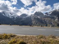 a motorcycle is parked on the side of the road with snow capped mountains in the background