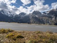 a motorcycle is parked on the side of the road with snow capped mountains in the background