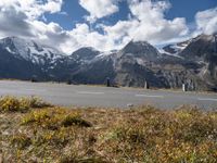 a motorcycle is parked on the side of the road with snow capped mountains in the background