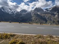 a motorcycle is parked on the side of the road with snow capped mountains in the background