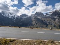 a motorcycle is parked on the side of the road with snow capped mountains in the background