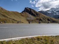 a motorcycle is parked on a road near a mountain range and snow capped peaks in the distance