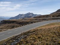 an empty road winding through mountains, on a clear day with no people around it