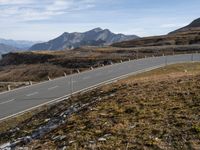 an empty road winding through mountains, on a clear day with no people around it
