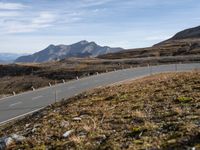 an empty road winding through mountains, on a clear day with no people around it