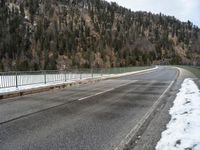 the skateboarder is skating down the snowy highway in the mountains outside of town