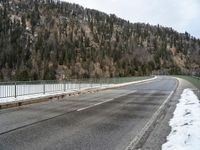 the skateboarder is skating down the snowy highway in the mountains outside of town