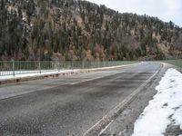 the skateboarder is skating down the snowy highway in the mountains outside of town