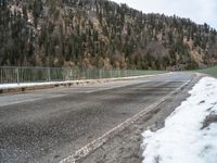 the skateboarder is skating down the snowy highway in the mountains outside of town