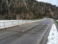 the skateboarder is skating down the snowy highway in the mountains outside of town