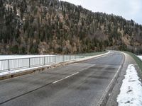 the skateboarder is skating down the snowy highway in the mountains outside of town