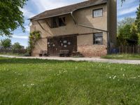 a brick building is on the side of a grassy hill side next to a gate and fence