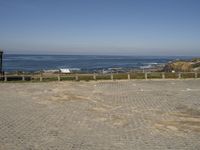 a brick paved area at the beach with a view of the ocean in the distance