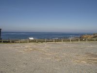 a brick paved area at the beach with a view of the ocean in the distance