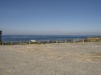 a brick paved area at the beach with a view of the ocean in the distance