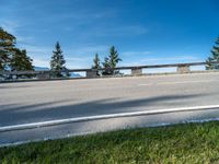 an empty highway has a wooden bench in the front of it, against a blue sky and hills