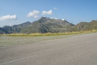 a motorcycle parked on the side of the road in a mountainous area, looking toward mountains