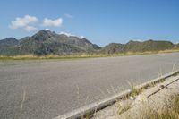 a motorcycle parked on the side of the road in a mountainous area, looking toward mountains