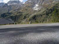 the back end of a motorcycle traveling down the road in a mountainous area with snowy mountains