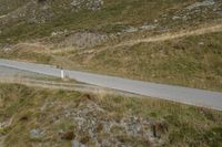 a sheep is walking down a steep hill by a road that goes to the top