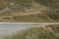 a sheep is walking down a steep hill by a road that goes to the top