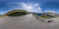 a fish eye view looking down the mountain road, with a view of the mountain range through the lens