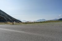 a bike rider going over a fence near the side of a road surrounded by mountains