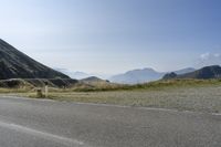 a bike rider going over a fence near the side of a road surrounded by mountains