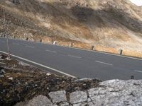 the guy on the motorcycle rides by the mountain road and waits at the roadside for the car