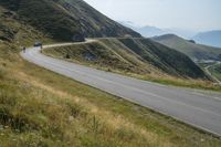 a view of an open mountain pass with motorcyclist on it and mountain in background