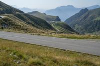 a view of an open mountain pass with motorcyclist on it and mountain in background