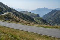 a view of an open mountain pass with motorcyclist on it and mountain in background