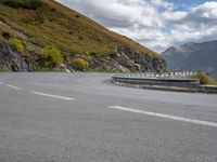 a man on a motorcycle rides down a mountain side road to get to another bike