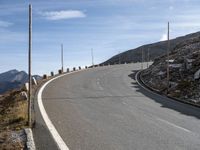 an empty road going uphill, in a mountainside setting and some rocks on either side