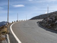 an empty road going uphill, in a mountainside setting and some rocks on either side