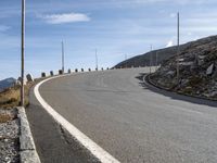 an empty road going uphill, in a mountainside setting and some rocks on either side