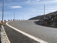 an empty road going uphill, in a mountainside setting and some rocks on either side