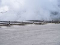 a skateboarder rides along a road past a mountain on a cloudy day with smoke