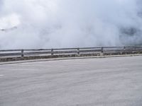 a skateboarder rides along a road past a mountain on a cloudy day with smoke