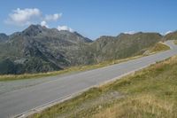 a lone motorcycle rider is riding down a long stretch of road through the mountains that stretches into the valley