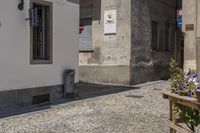 flower pot and a small wooden bench by a white building with two signs on it