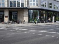 a city street that is mostly paved with concrete and sidewalking, and bicycles parked on it